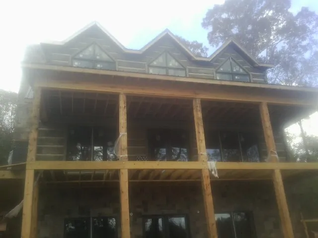 Dormers and porch framing on a large log home under construction — Roof Coating work by our crew in Bentonville
