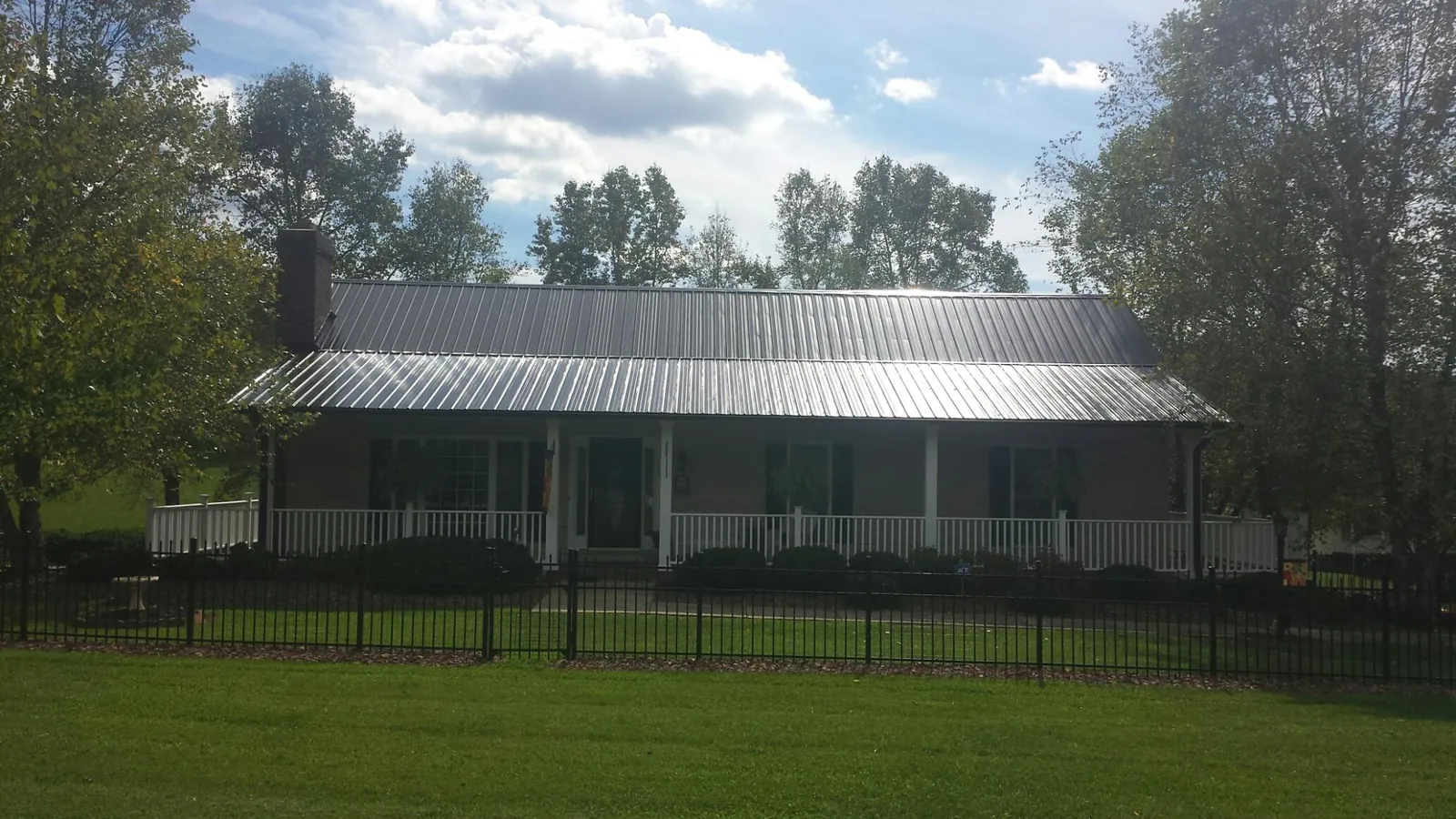 Gray metal roof on a brick ranch with a full width front porch — Gutter Guard Installation work by our crew in Bentonville